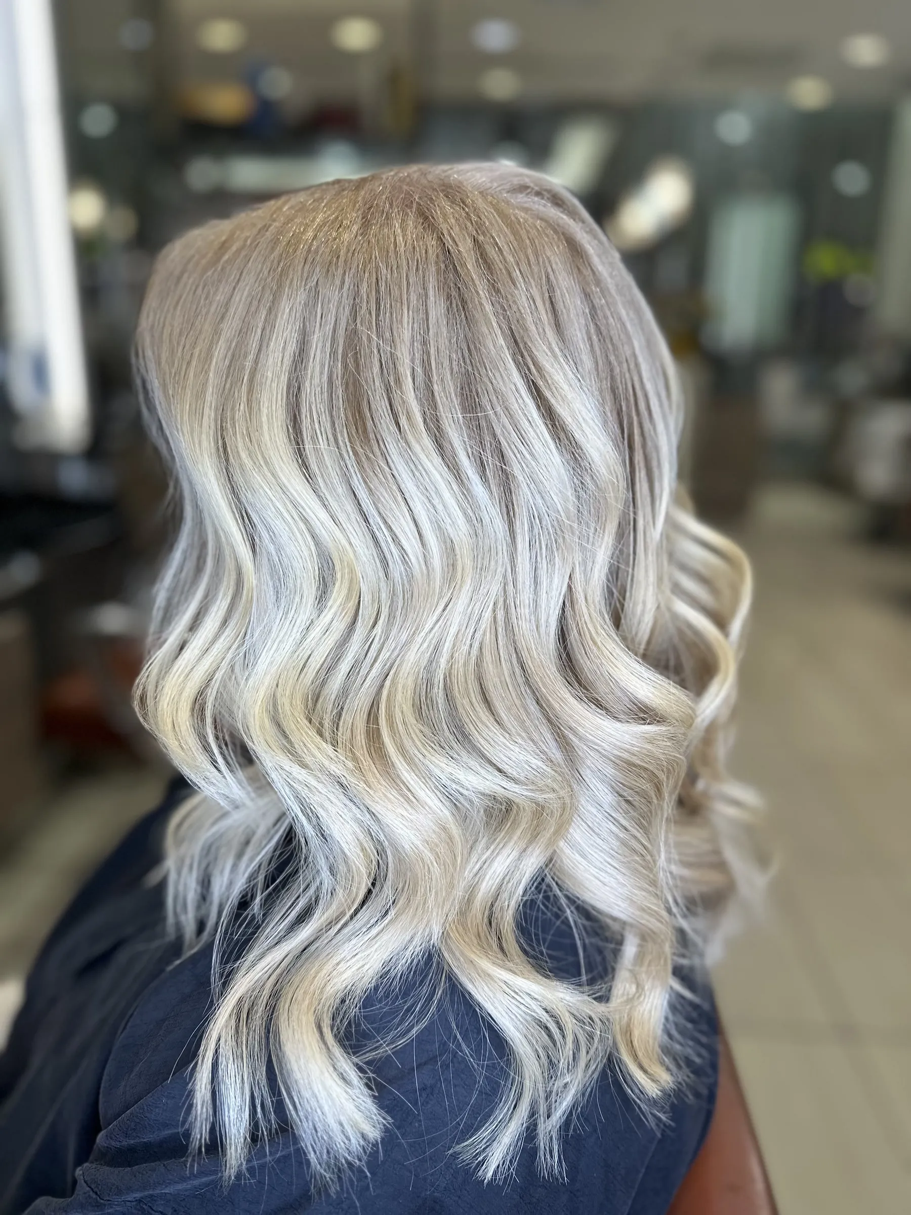 Icy blonde balayage with a soft root on shoulder-length waves by Ronak Hairstylist in Toronto