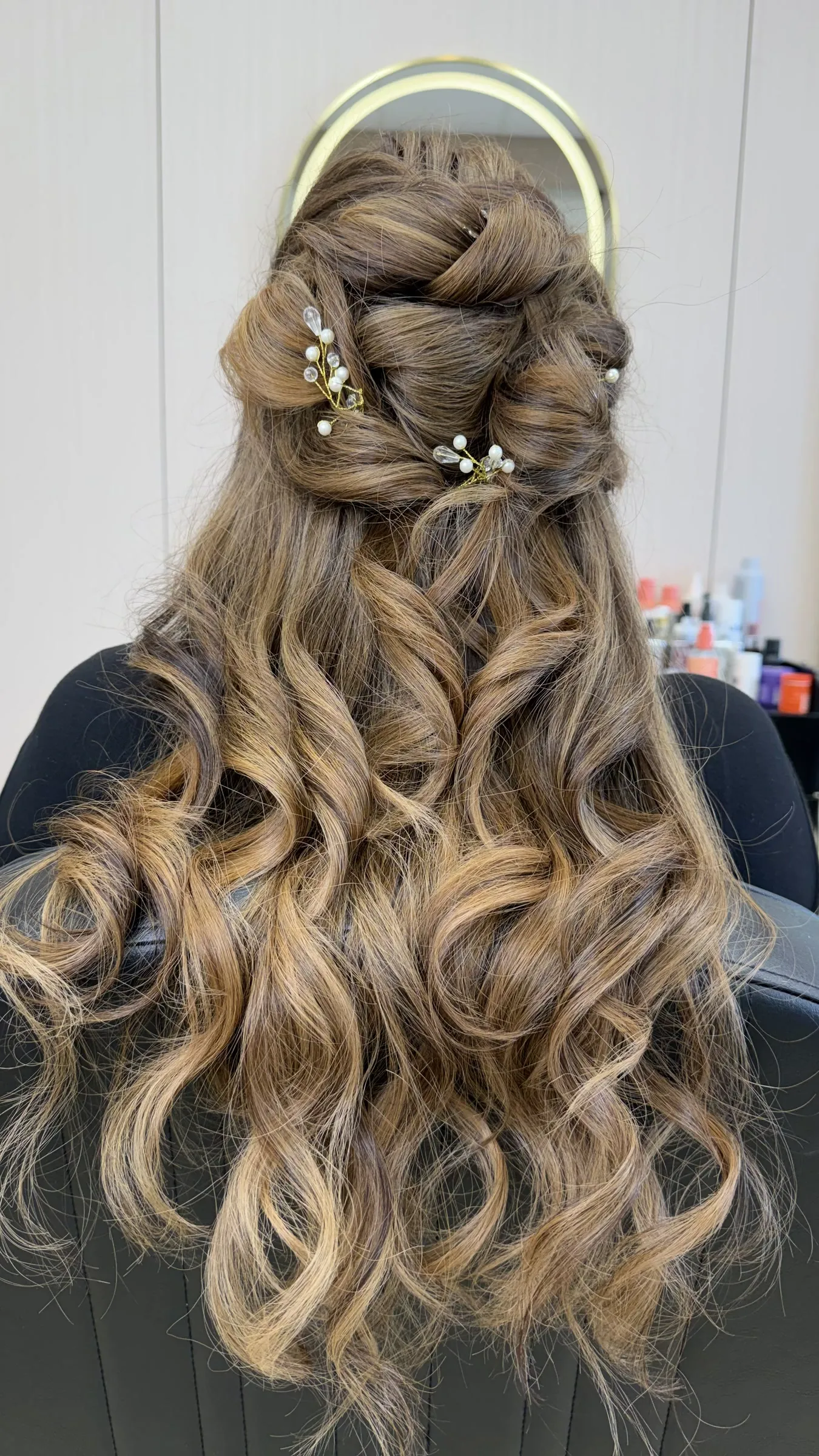 Half-up braided style with pearl pins and long curls by Ronak Hairstylist in Toronto