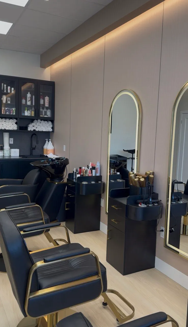 Black and gold styling chairs and arched mirrors inside Ronak Hairstylist's salon in Toronto